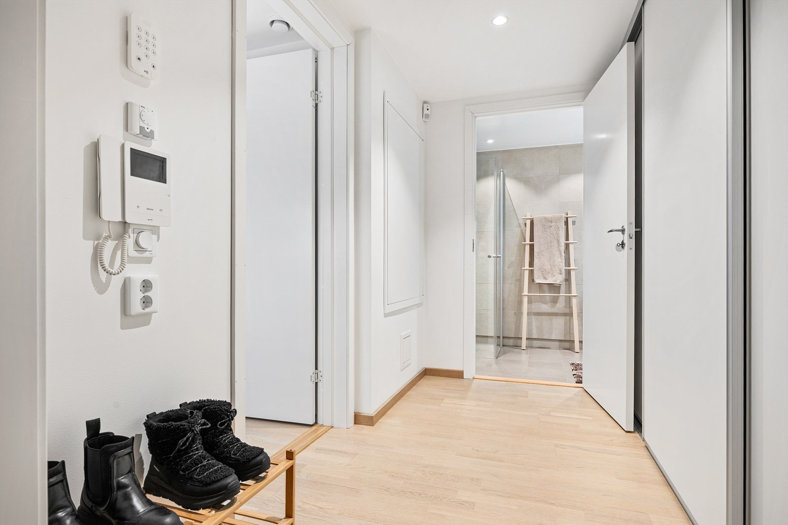 Leiligheten har en gjennomgående lys fargepalett med lyse veggflater og lyst parkettgulv. Bak hvite skyvedører har entréen et garderoberom for praktisk oppbevaring. Galleribilde