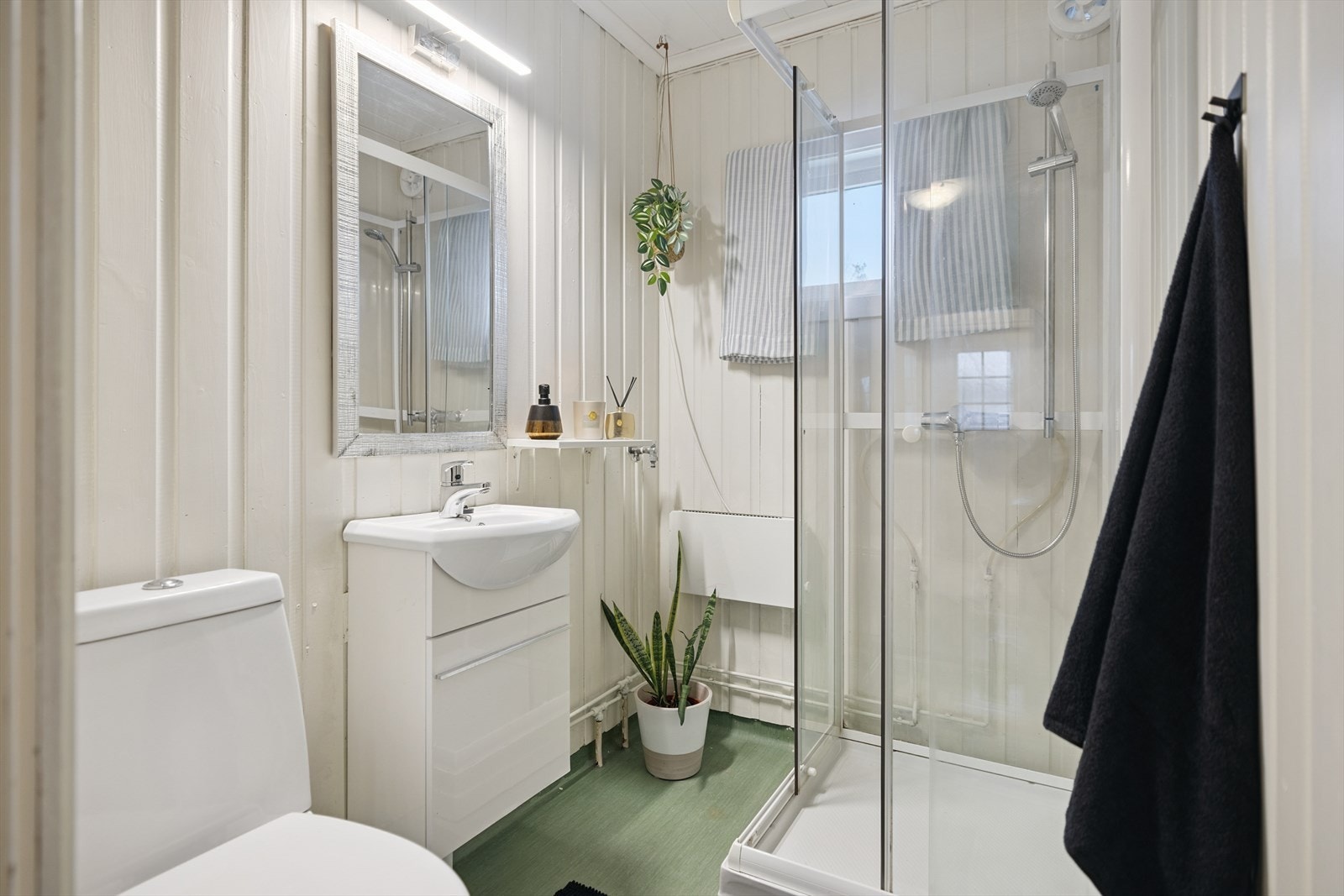 Badet er utstyrt med servantmøbel, toalett og dusjkabinett. Galleribilde