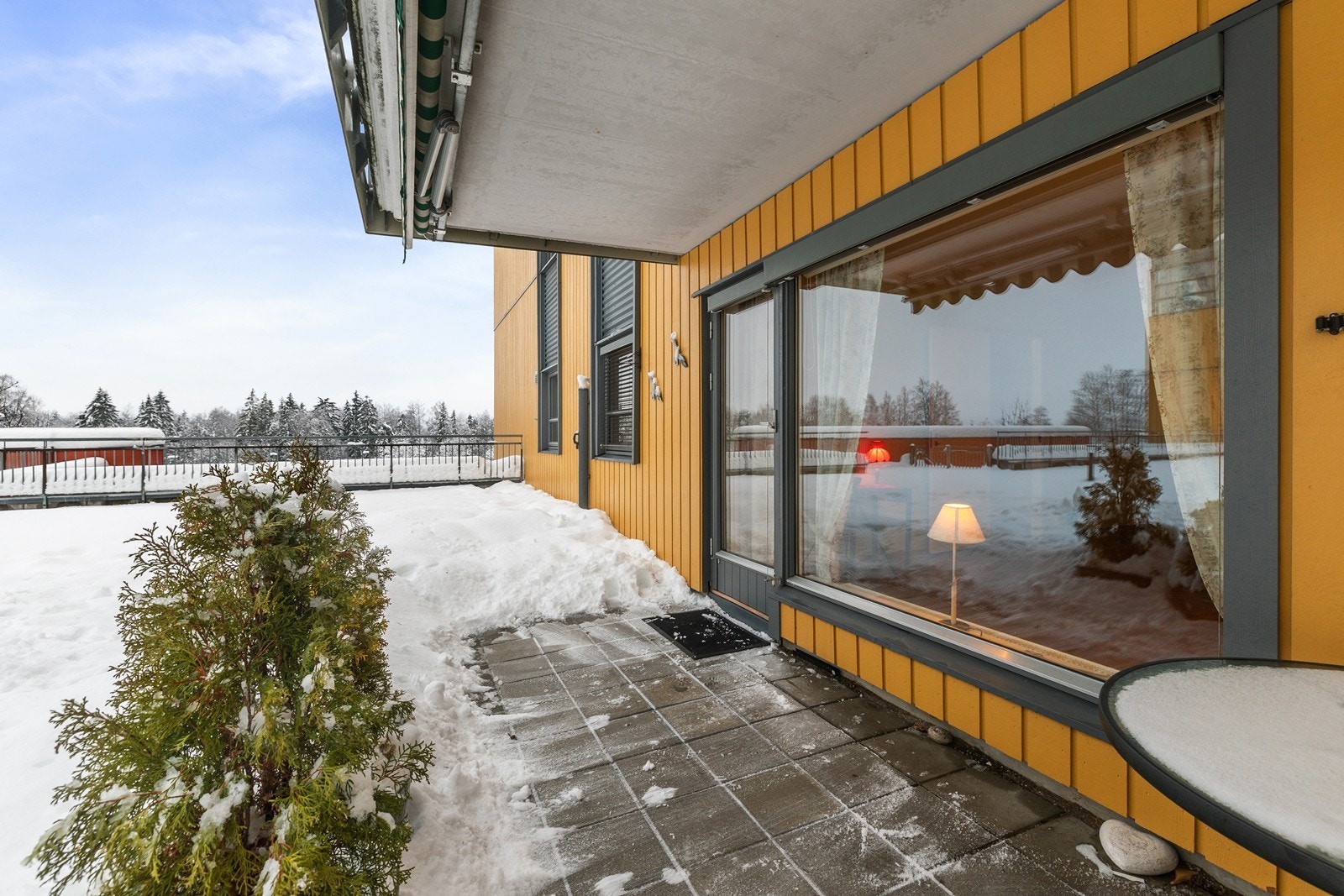 Leiligheten har utgang fra stue til en romslig terrasse med steinheller og utsikt over fellesareal. Galleribilde