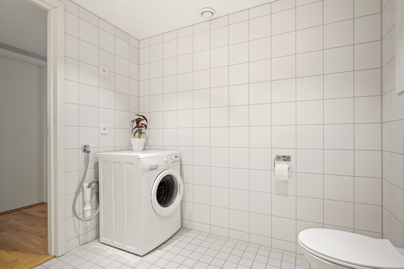 Romslig flislagt bad/vaskerom med opplegg for vaskemaskin og tørketrommel Galleribilde