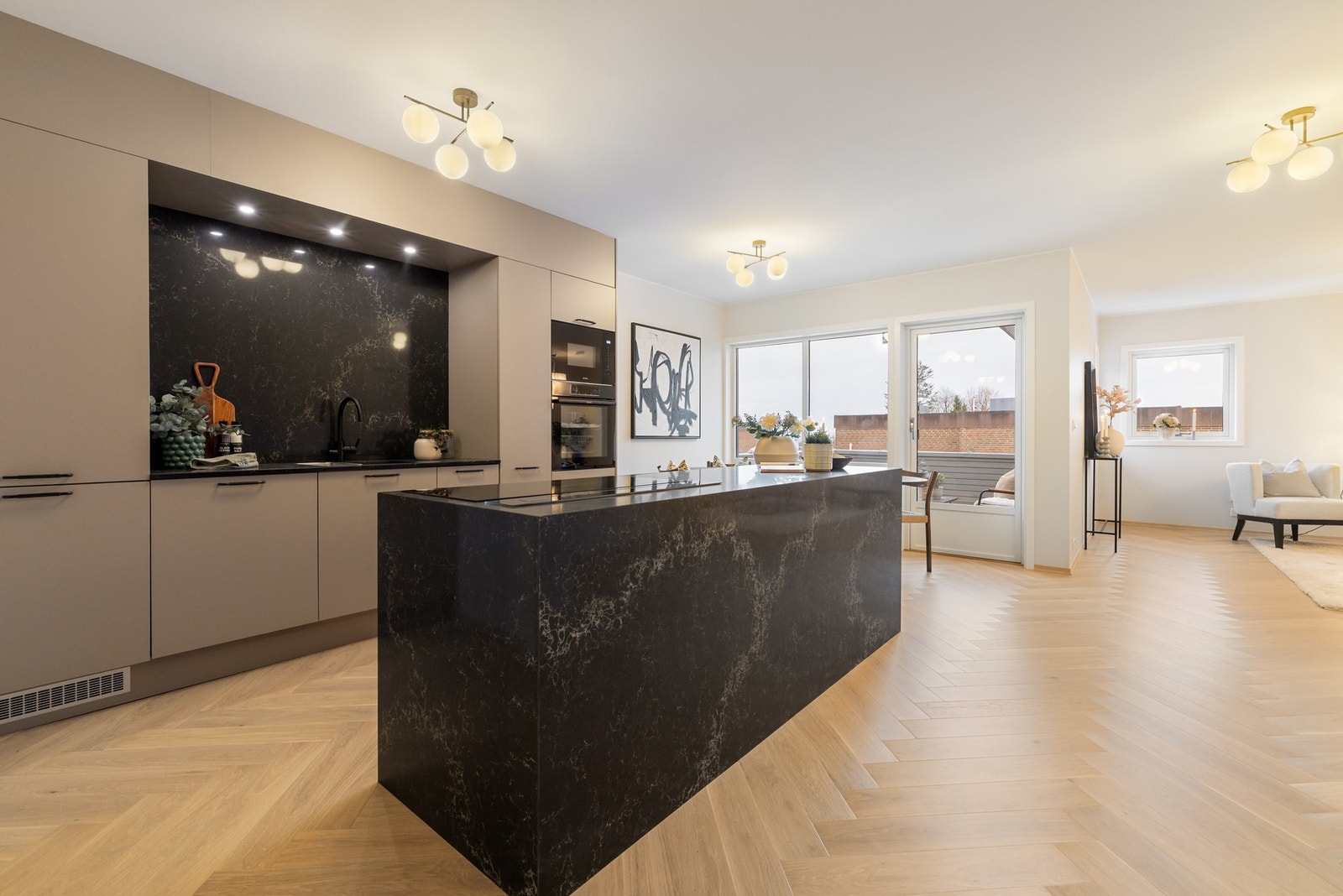 Eksklusivt kjøkken med benkeplate i komposittstein samt waterfall- og veggplate i stein. Galleribilde