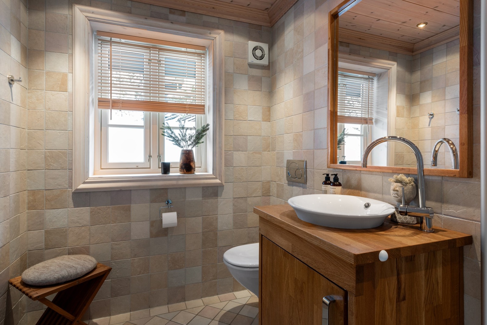 Badet er innredet med toalett, dusj og servant med innredning. Galleribilde