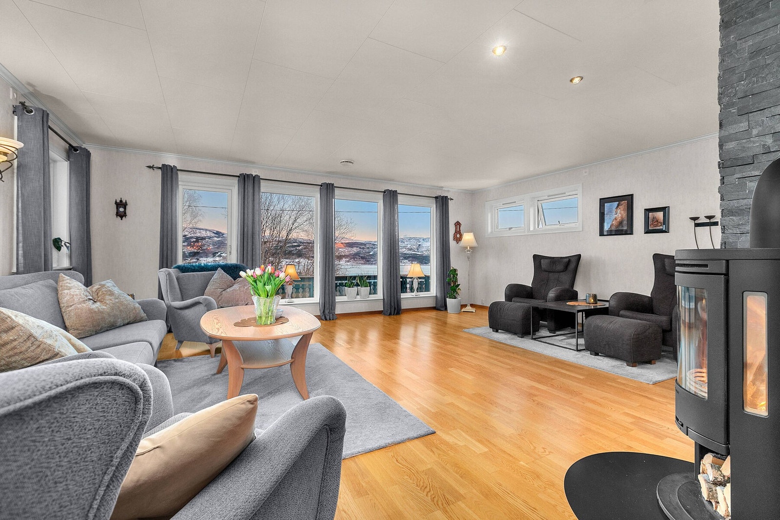 Romslig stue med store vindusflater, parkett på gulv og spotter i tak. Galleribilde