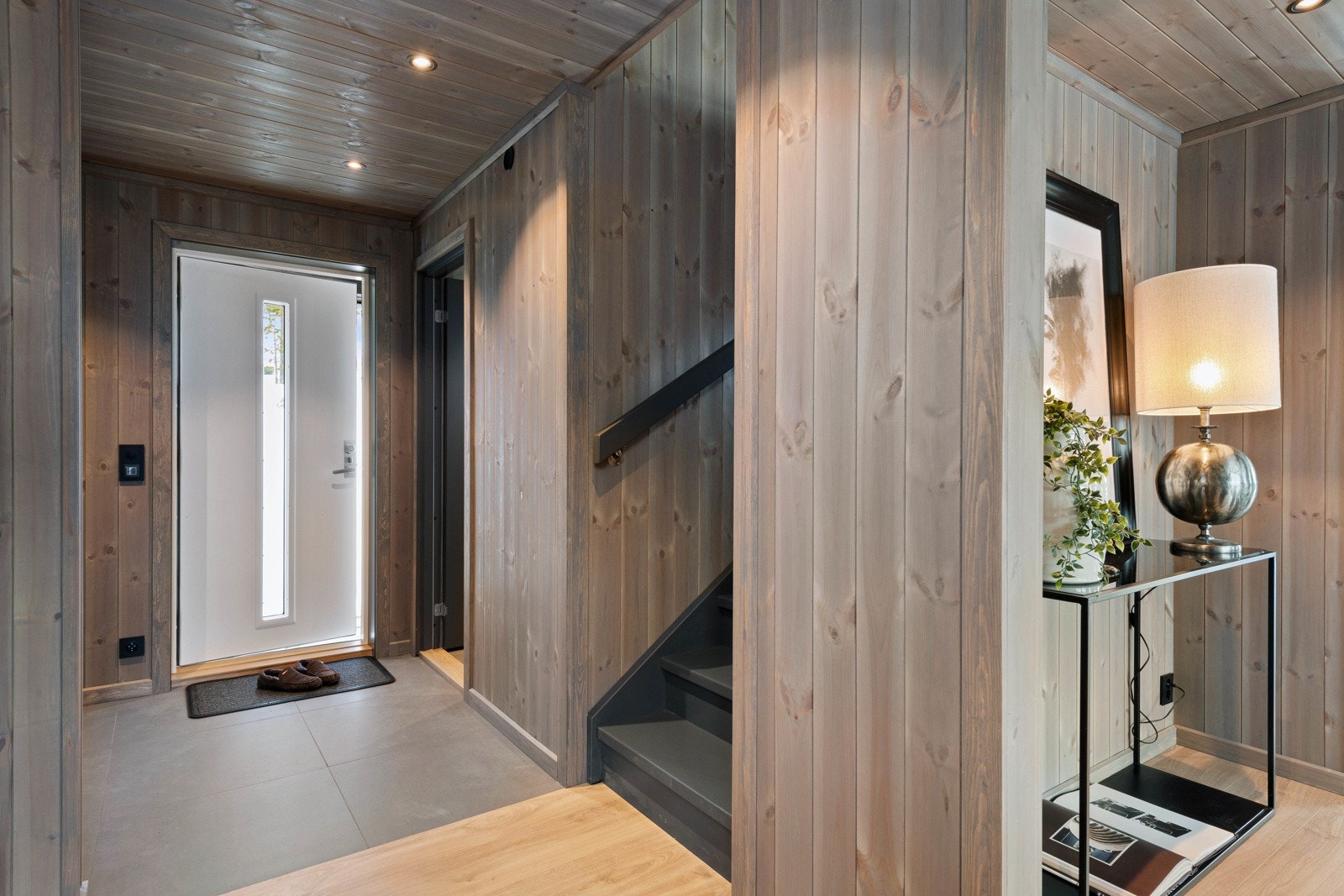 Entreen har grå fliser på gulv med gulvvarme, beisede paneloverflater på vegger og tak, downlights i taket og plass til garderobe. Galleribilde