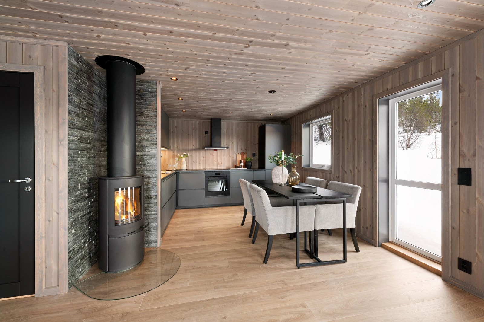 Muren bak ildstedet er kledd i naturstein som står godt til det grå kjøkkenet. Galleribilde