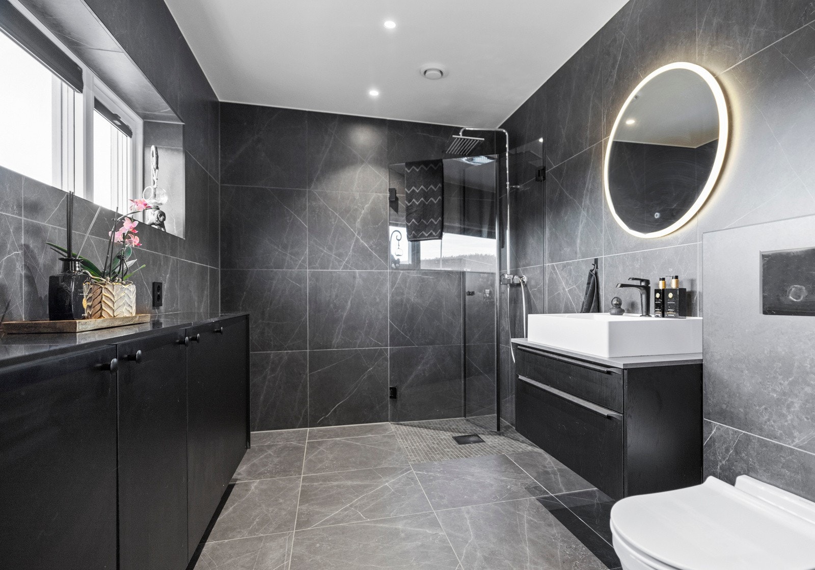 Badet i første etasje er en moderne oase med flislagte overflater som gir et rent og stilig uttrykk Galleribilde