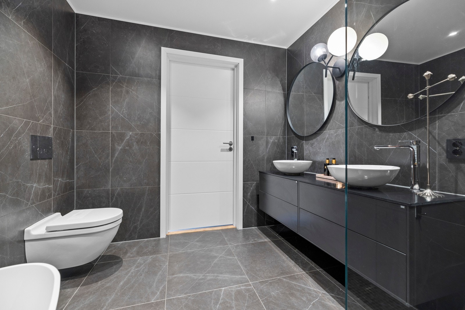 Her har du praktiske løsninger med vegghengt toalett og en dobbelservant med masse oppbevaringsplass Galleribilde