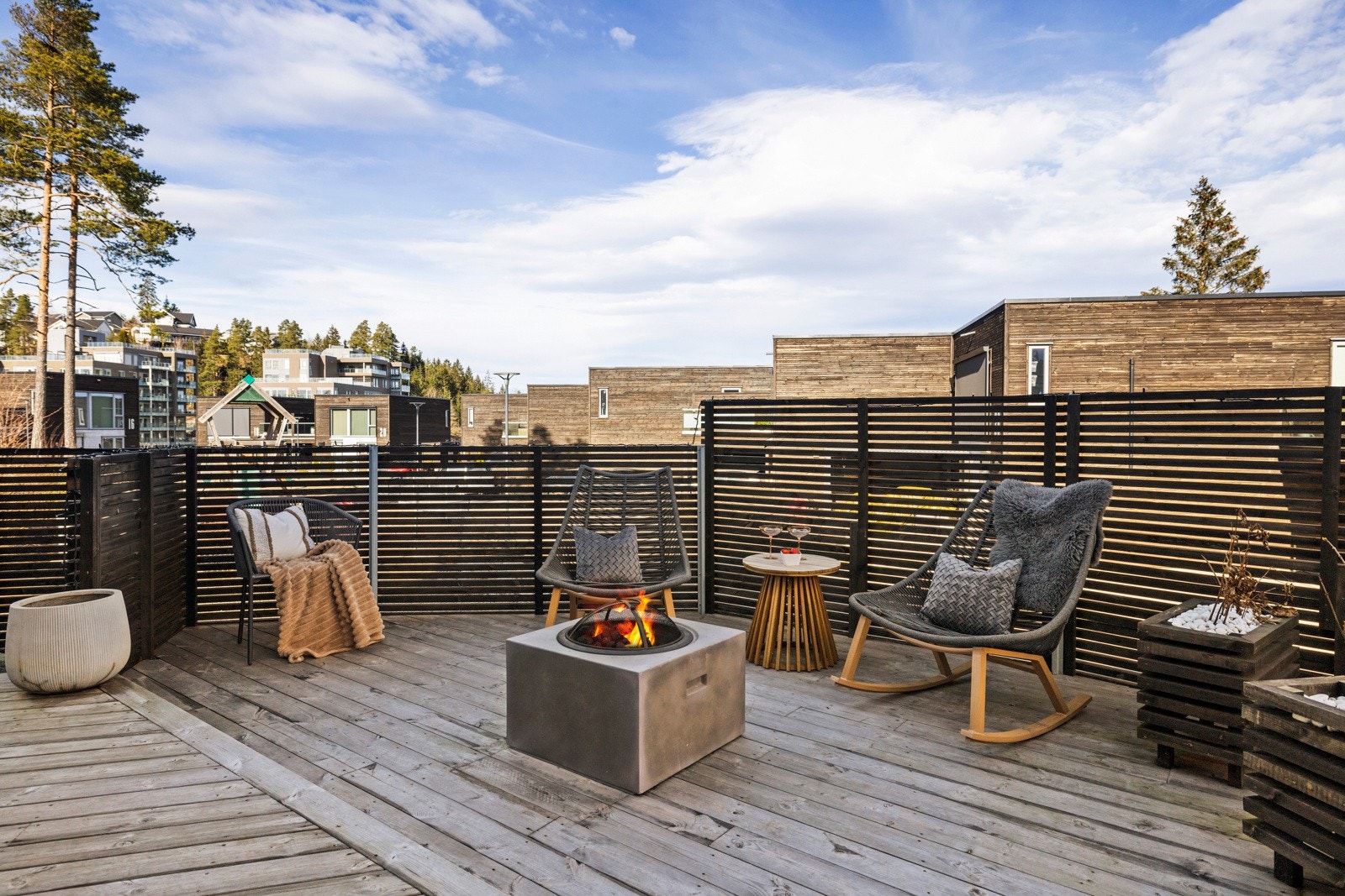 Rekkverket og leveggen av tre gir både privatliv, sikkerhet og en lun plass for en bålplass Galleribilde