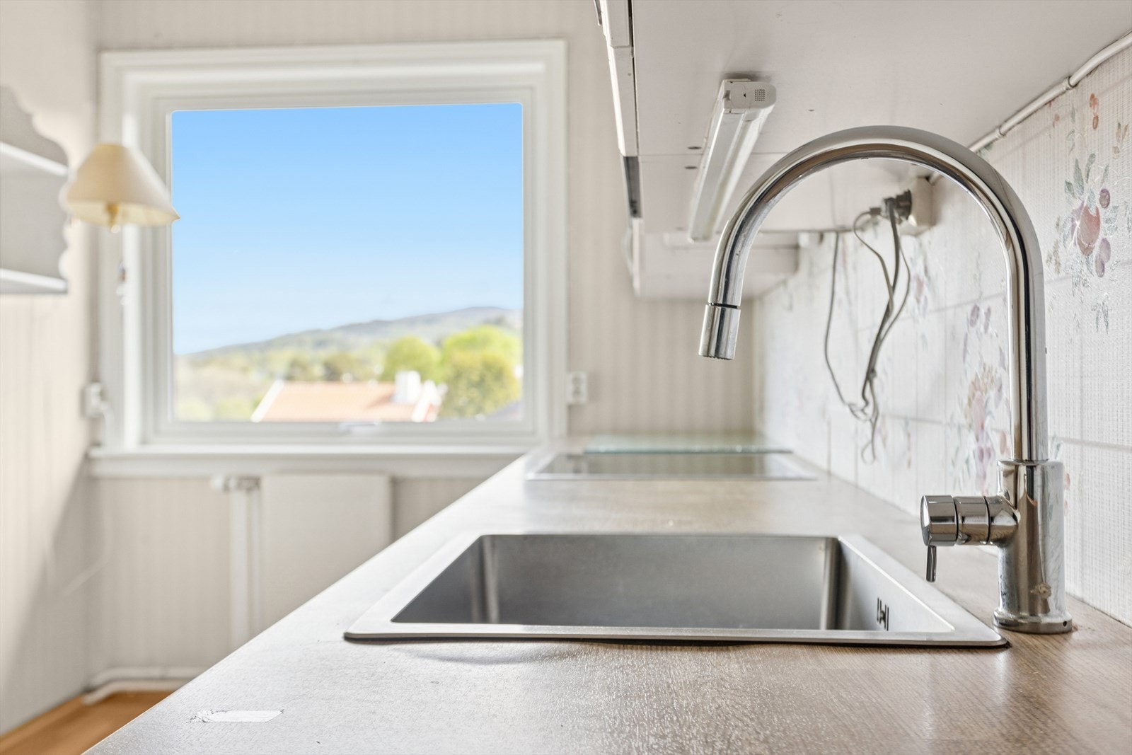 Detalj av kjøkkenbenk med stålvask og moderne kran. Praktisk utførelse som gjør matlaging og rengjøring enkelt. Galleribilde