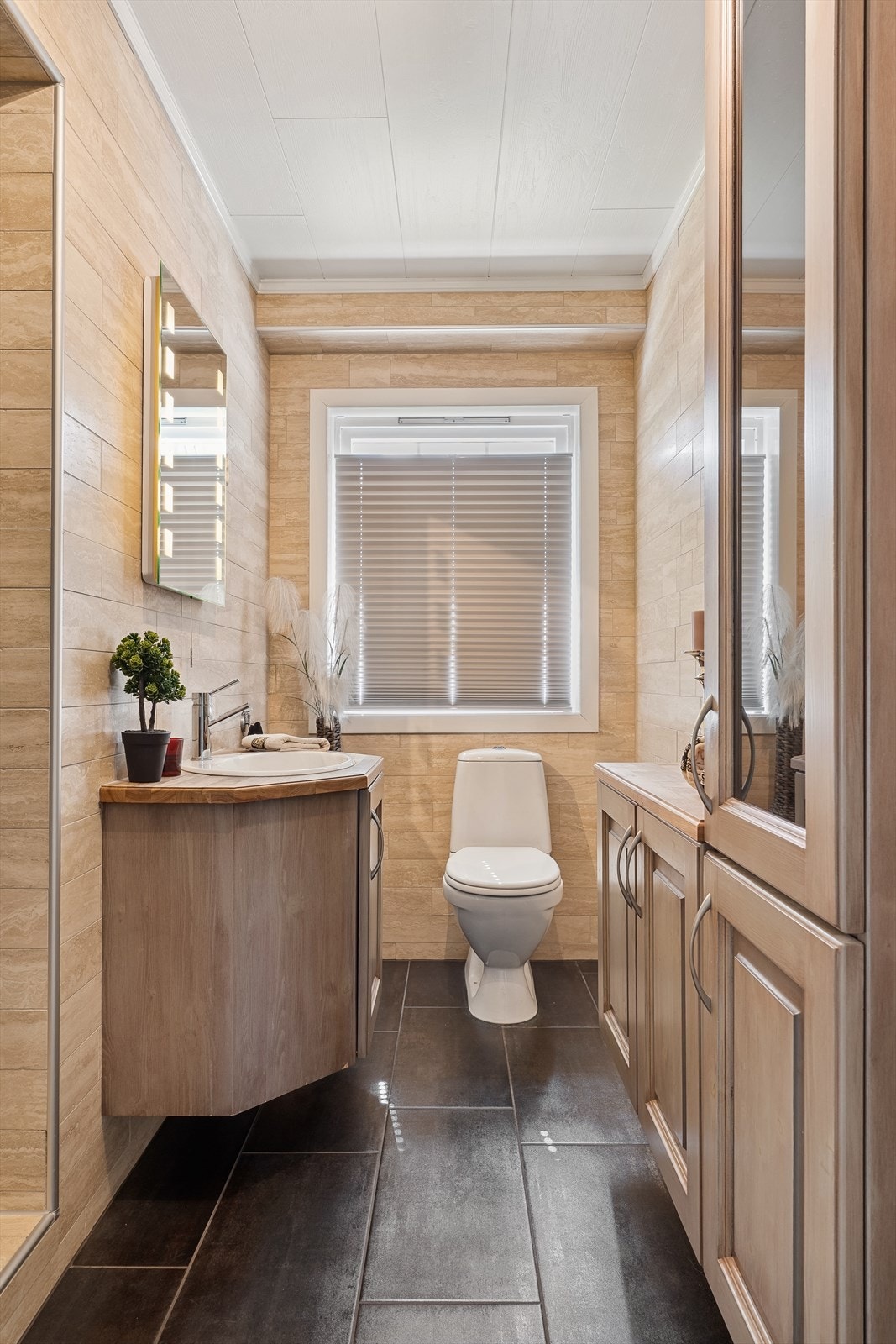 Badet i første etasje har flislagte overflater, servant med underskap og varme i gulvet. Galleribilde