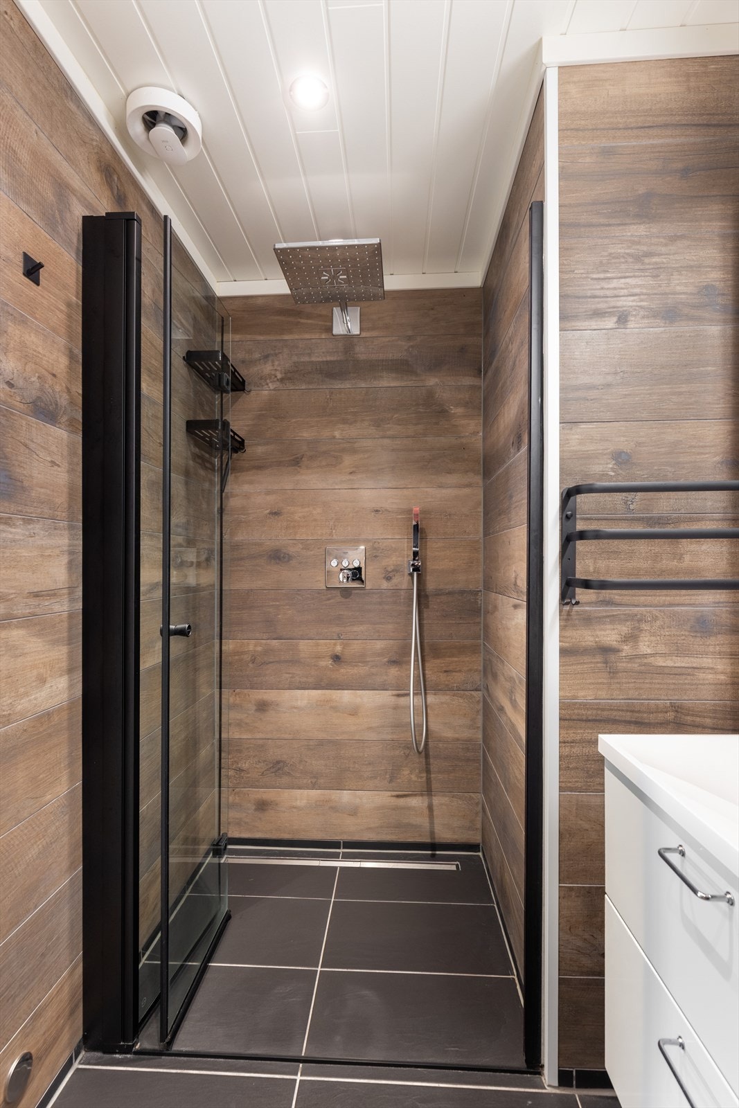 Badet har en gjennomført stil med sorte baderomsdetaljer, samt at det er etablert dusjnisje i stilrent design med sorte profiler. Galleribilde