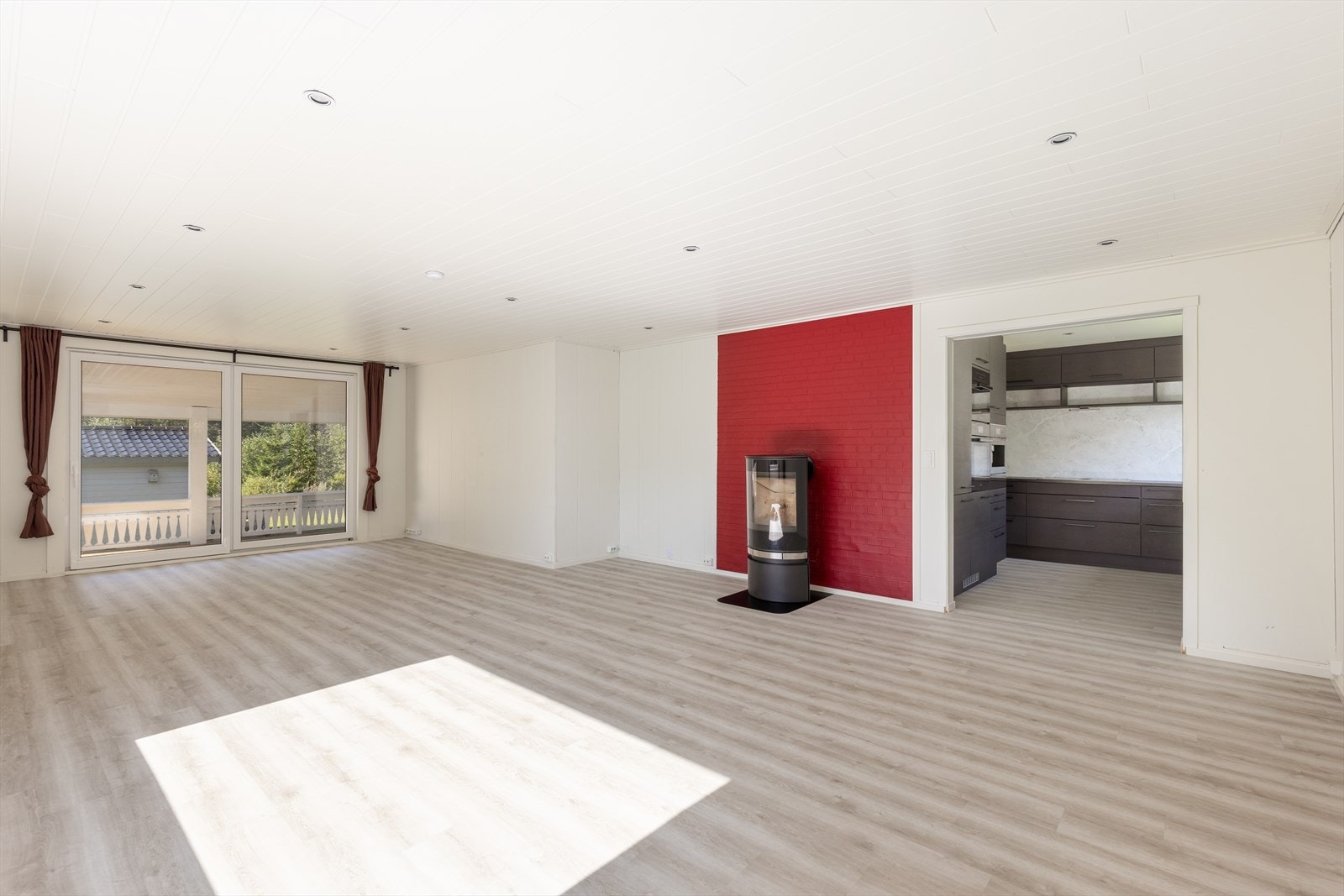 Den romslige stua med åpen løsning inn mot kjøkkenet har gode møbleringsmuligheter. Her er det installert ny, moderne vedovn fra 2021 med glassdør og plate på gulvet. Galleribilde