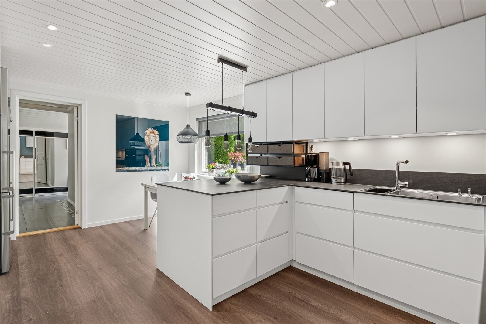 Detaljrikt kjøkken med skap helt opp til tak, integrerte hvitevarer, keramisk benkeplate, Røroshetta og gode hvitevarer. Galleribilde