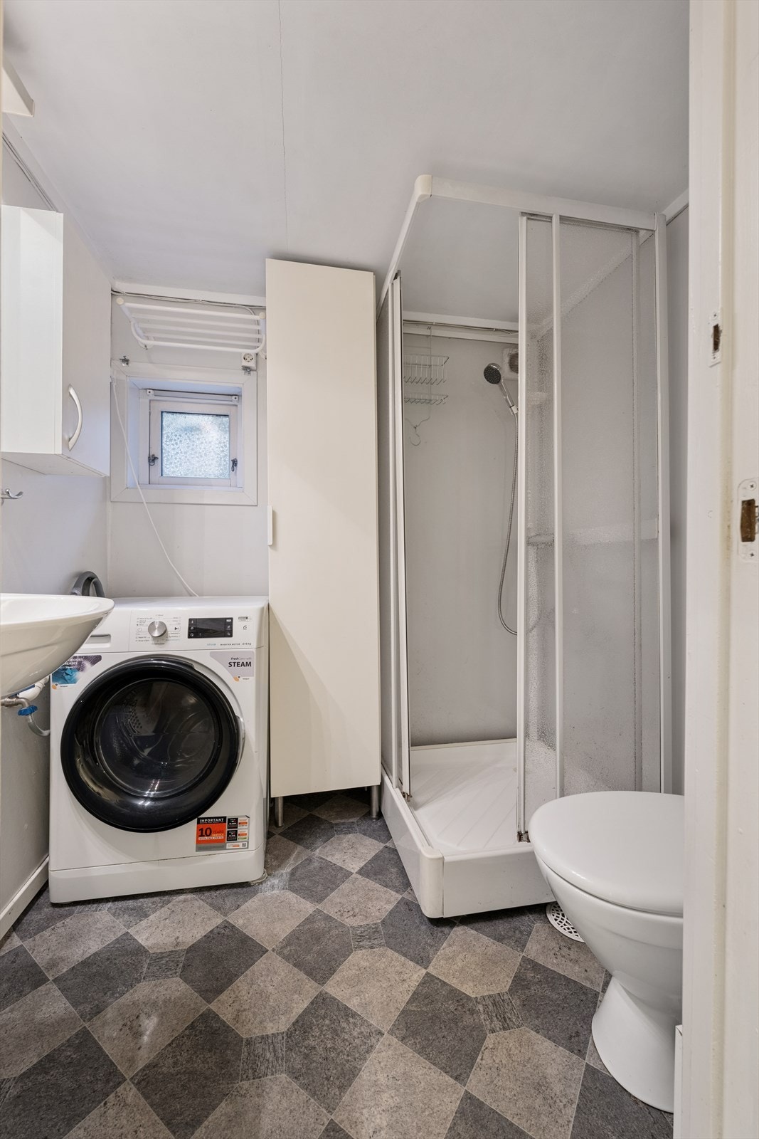 Det andre baderommet i 1. etasje er innredet med servant, toalett, dusjkabinett og opplegg for vaskemaskin. Galleribilde