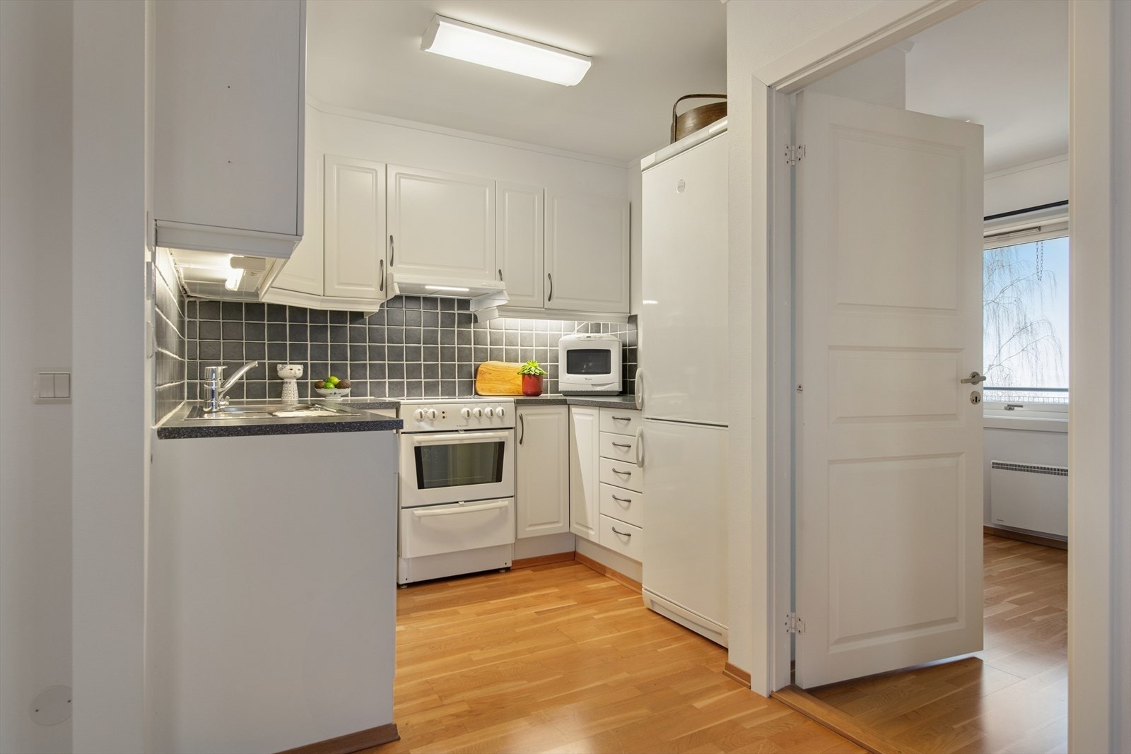 Pent kjøkken med lys, tresidet innredning. Galleribilde