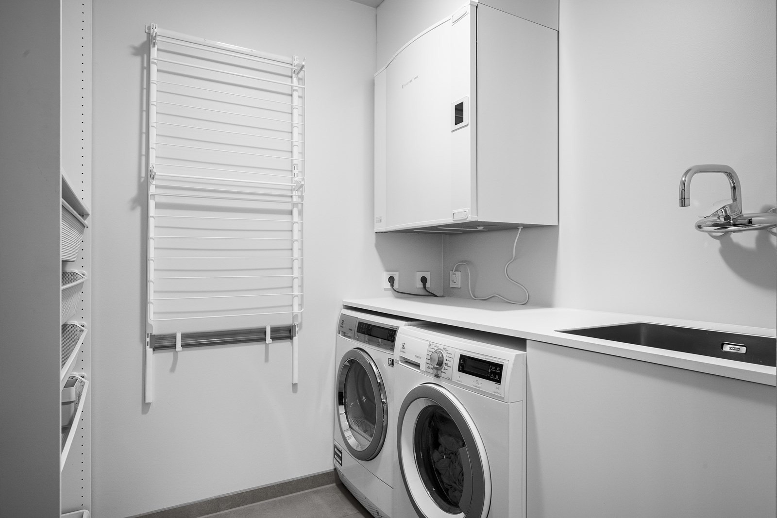 Et svært praktisk vaskerom med hylleløsninger og oppheng som lar tilfredsstiller hverdagsbehovet for ulike sesonger og yttertøy. Utslagsvask of praktiske formål. Galleribilde