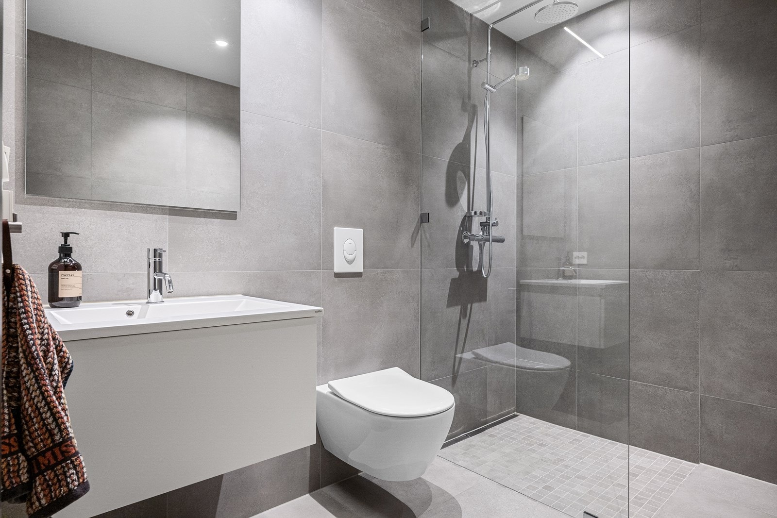 Delikat og tidløst. Nedsenket dusjsone og glassvegg for skjerming. Vannfallsdusj og håndholdt. Stilrene sluk langs vegg på begge bad. Galleribilde