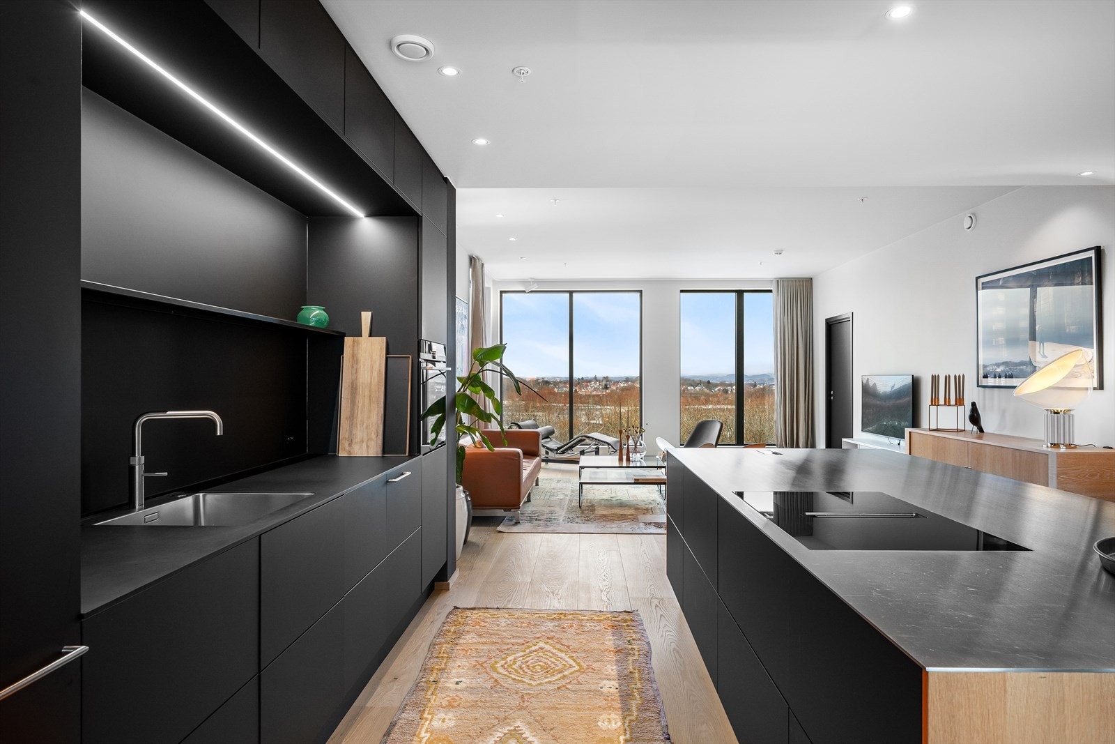 Rene linjer og myke overganger. Gjennomgående naturlig lys og formidabel utsikt. Ledlys og spotter for kokken på kveldsvakt. Galleribilde