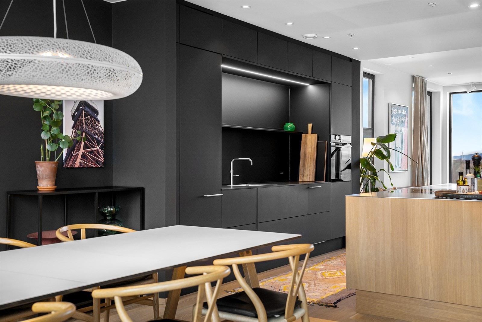 Stramt og mykt i harmoni. Et møbel av et kjøkken som glir sømløst inn i helheten. Rikelig med skapplass og lagring, samt arbeidsplass. Fin kontakt med spisestuen - som du kan dra ut til høytider. Galleribilde