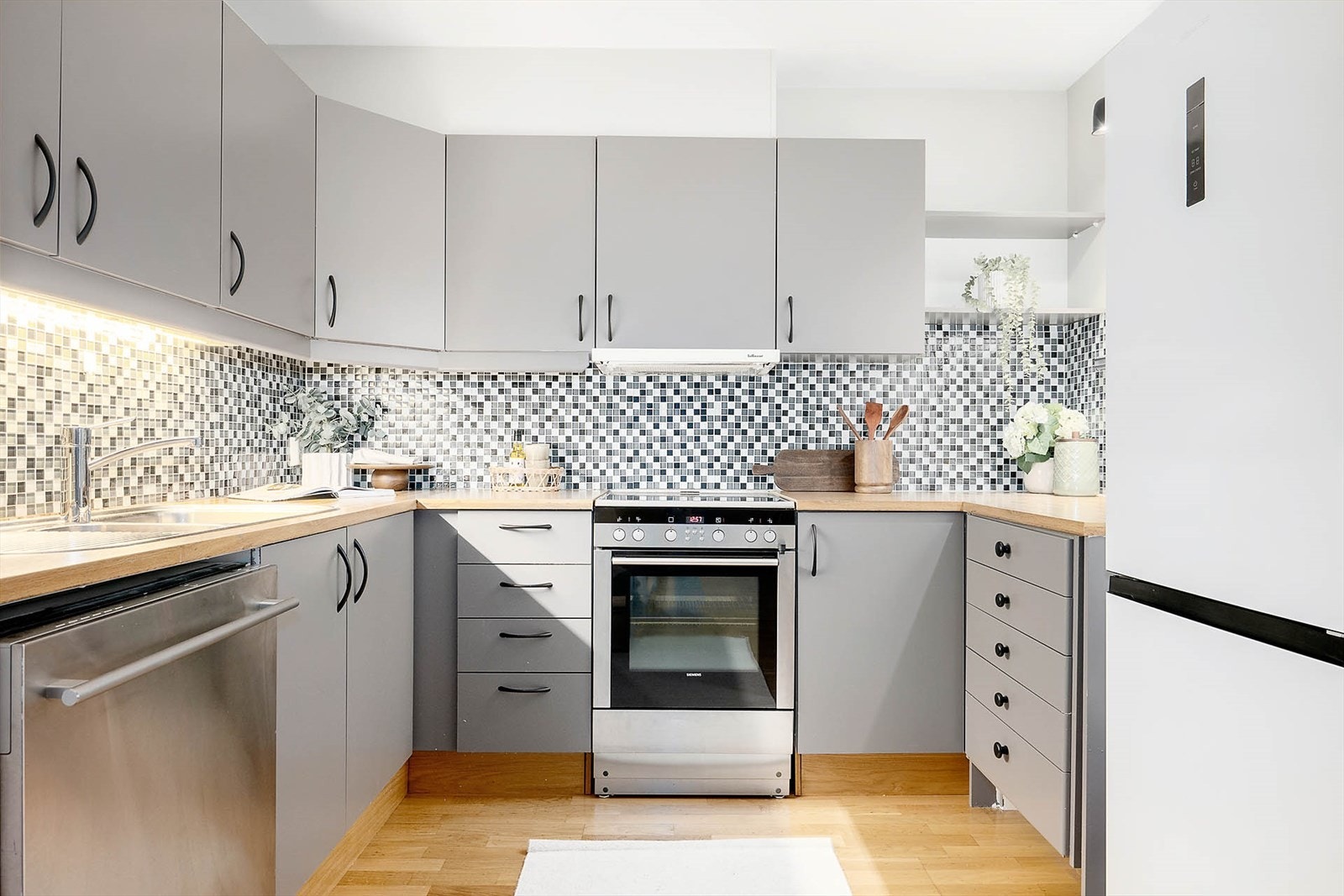 Oversikt over kjøkkenet - gjennomtenkt plassering av hvitevarer og skap gjør rommet både funksjonelt og ryddig. Galleribilde