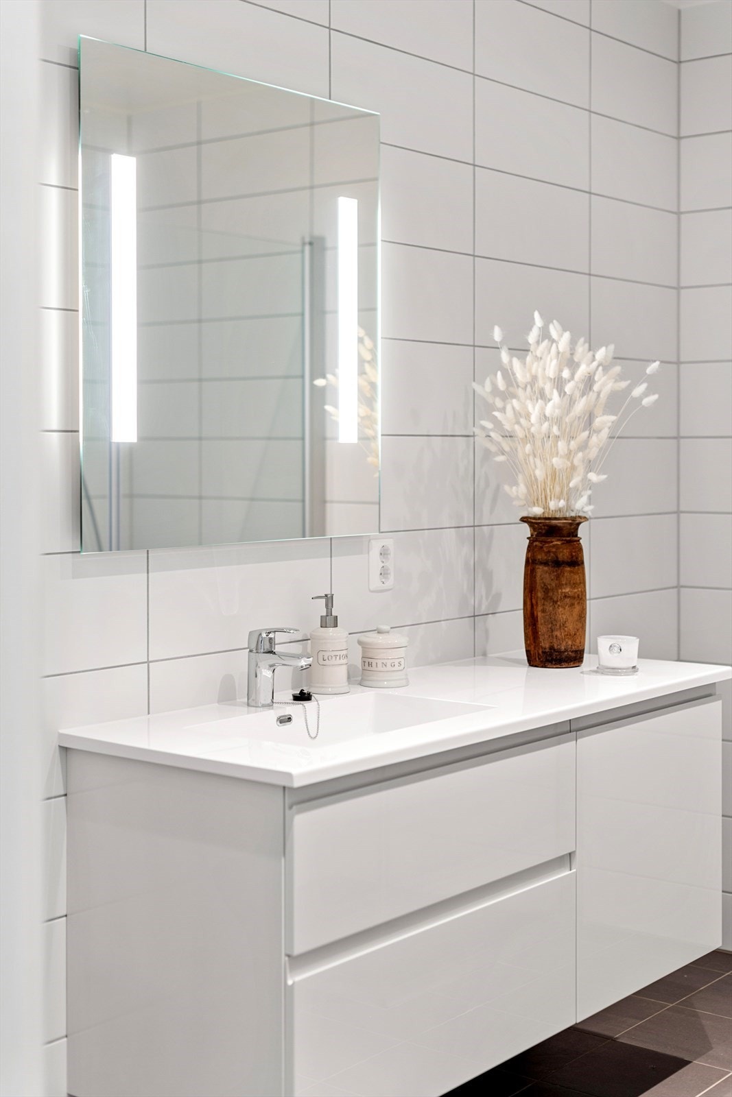 Innredningen har hvite, glatte skuffefronter, heldekkende servant og speil med integrert belysning Galleribilde