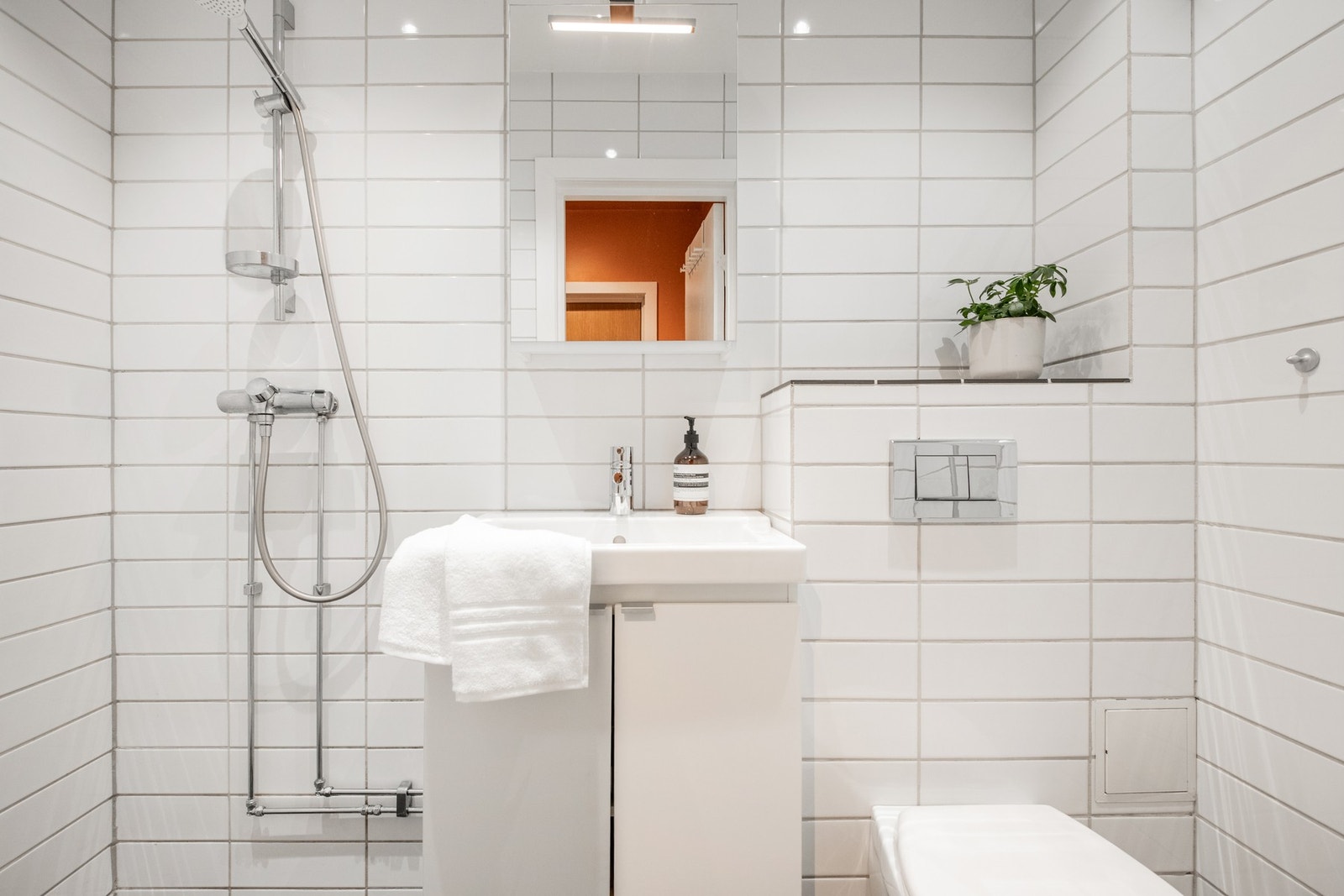 adet fremstår lyst og tidsriktig med hvite, liggende veggfliser i format 30 × 10 cm, malt himling og flislagt gulv med behagelige varmekabler som gir ekstra komfort i hverdagen. Galleribilde