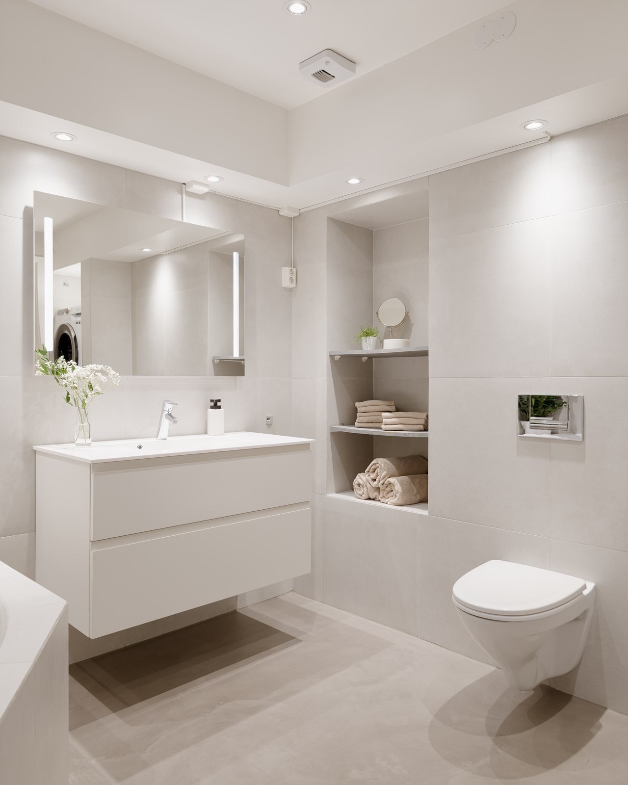 Badet inneholder vegghengt toalett, dusj, badekar, servant med ett-greps blandebatteri og servantskap. Galleribilde