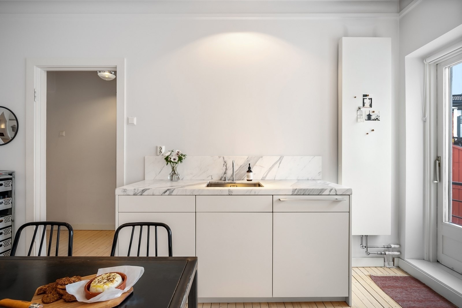 Lys innredning med glatte fronter, komposittbenkeplate og marmorbenkeplate rundt oppvaskkummen. Galleribilde