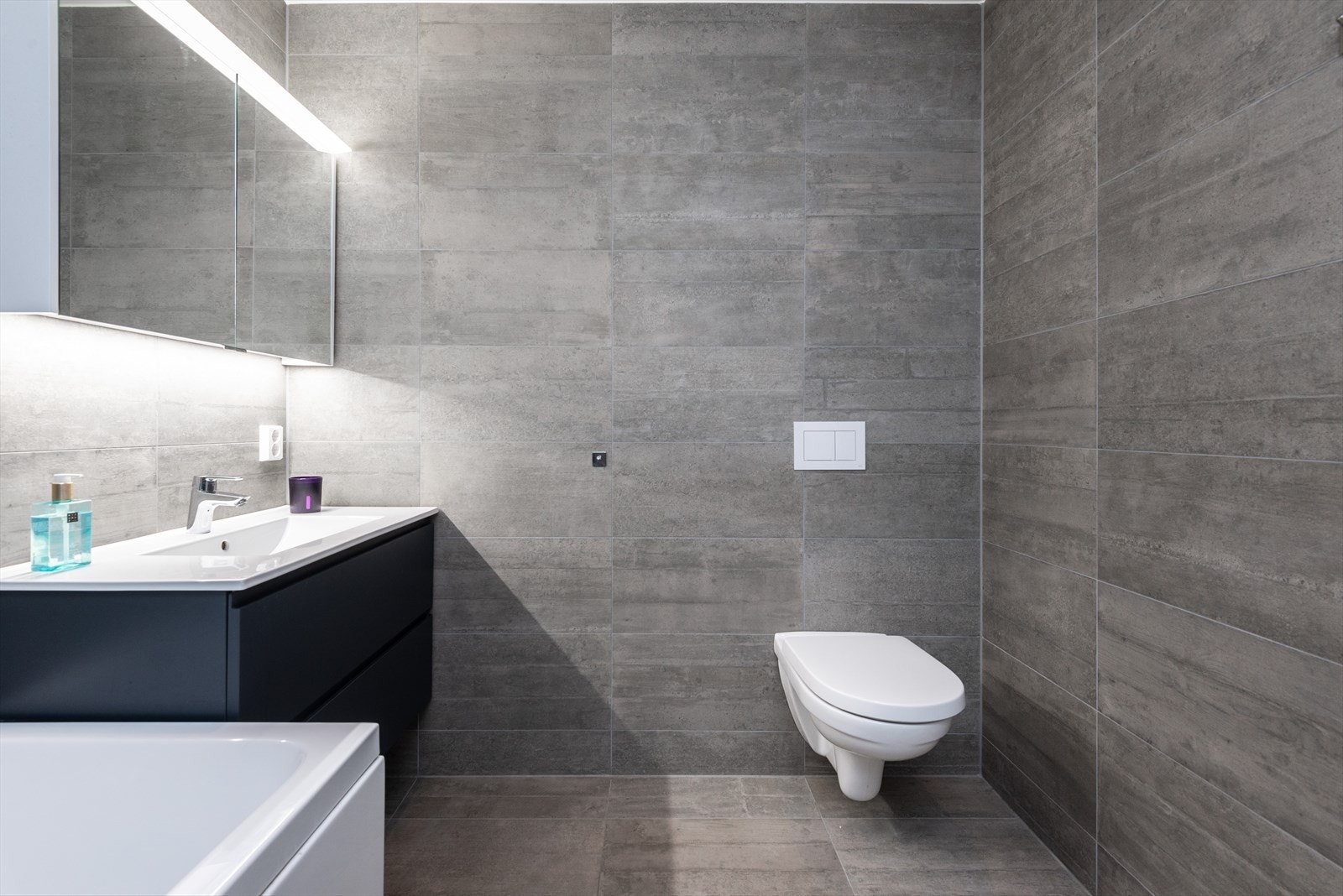 Vegghengt toalett og speilskap med belysning gir et effektivt og ryddig baderom. Galleribilde