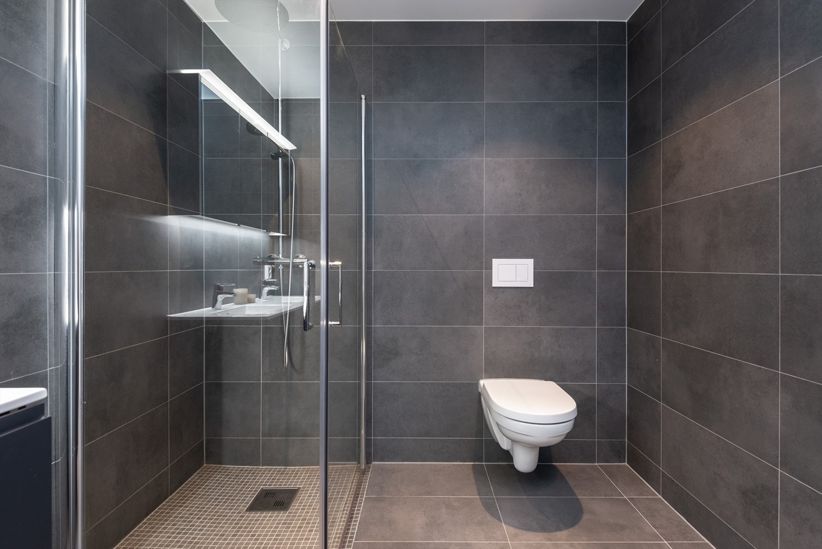 Vegghengt toalett og dusj med glassdører sikrer et stilrent våtromsdesign. Galleribilde