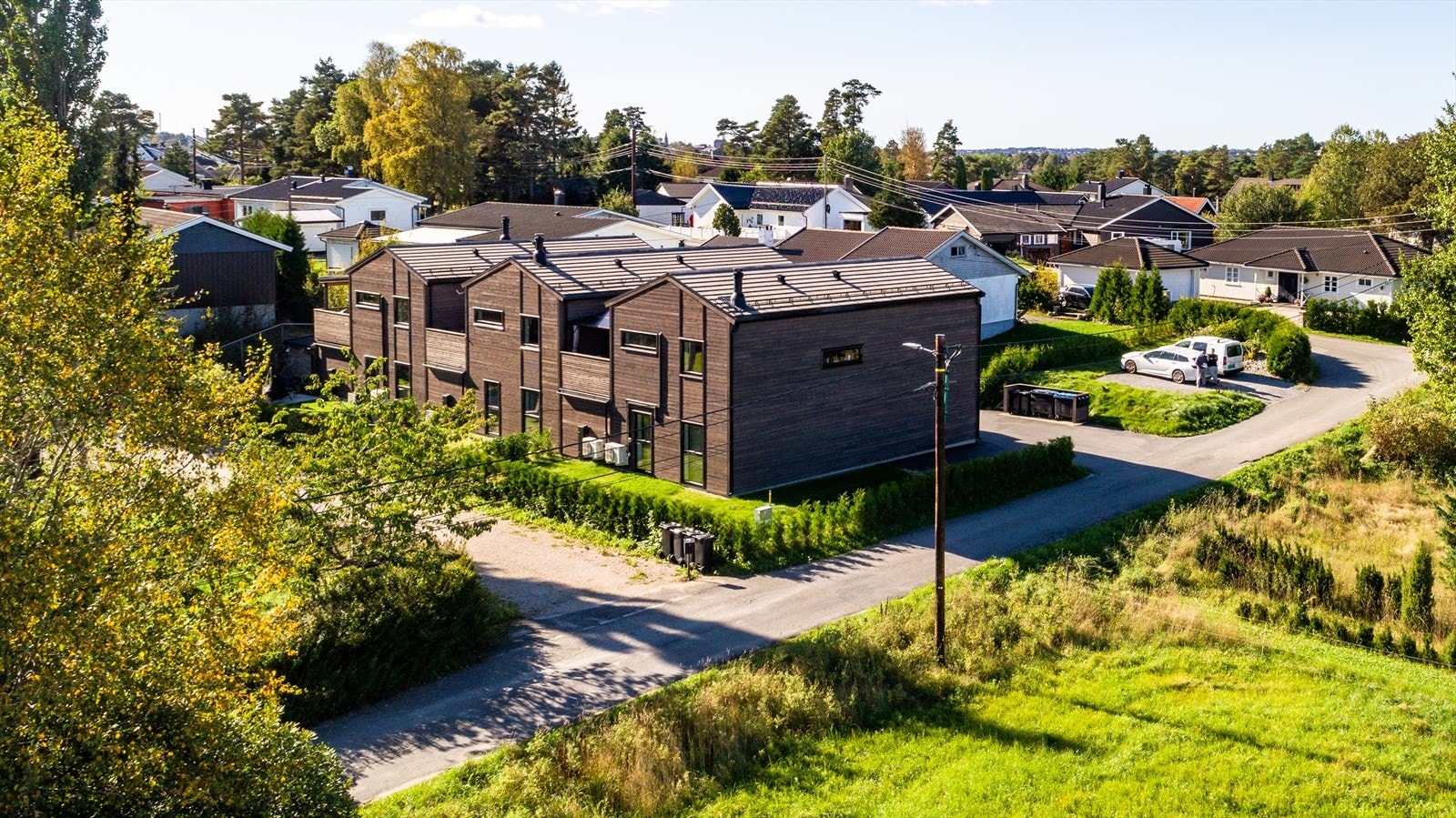 Boligen har stående og liggende malt trepanel fra 2022, med asfaltert gang- og parkeringsarealer. Galleribilde