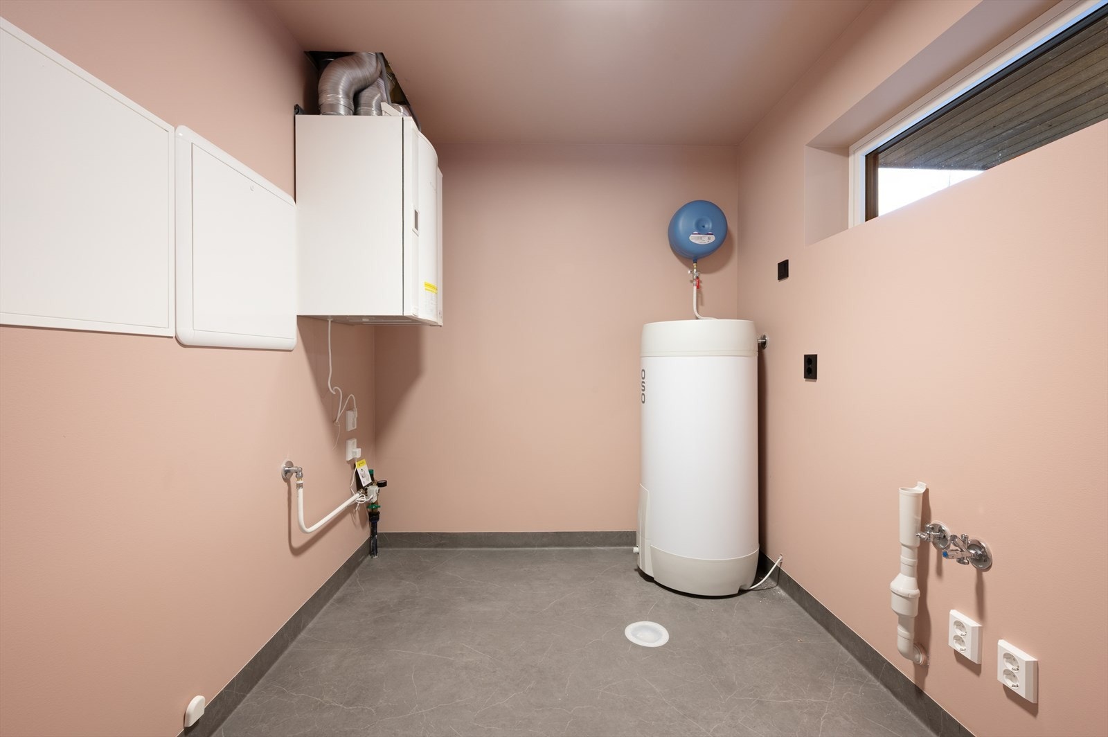 Praktisk vaskerom med rørfordelingsskap, varmtvannsbereder, systemskap for ventilasjonsanlegg og opplegg for vaskemaskin. Galleribilde