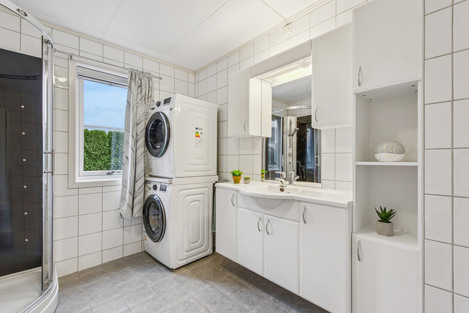 Lyst og pent bad med opplegg til vaskemaskin og tørketrommel. Galleribilde