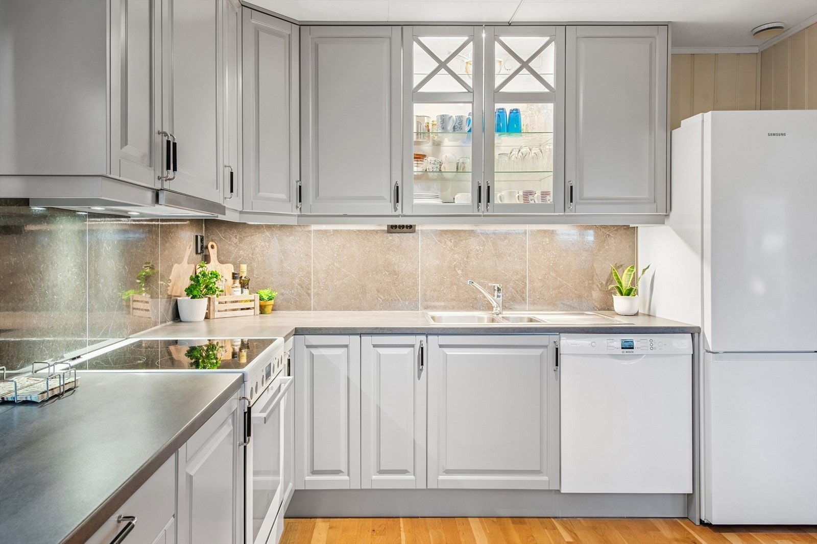 Kjøkkeninnredning med profilerte fronter, vitrineskap med belysning og godt med benkeplass. Galleribilde