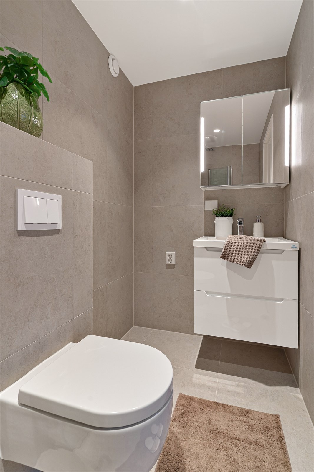 Her er det vegghengt toalett, servant med skuffer og speilskap med belysning. Galleribilde