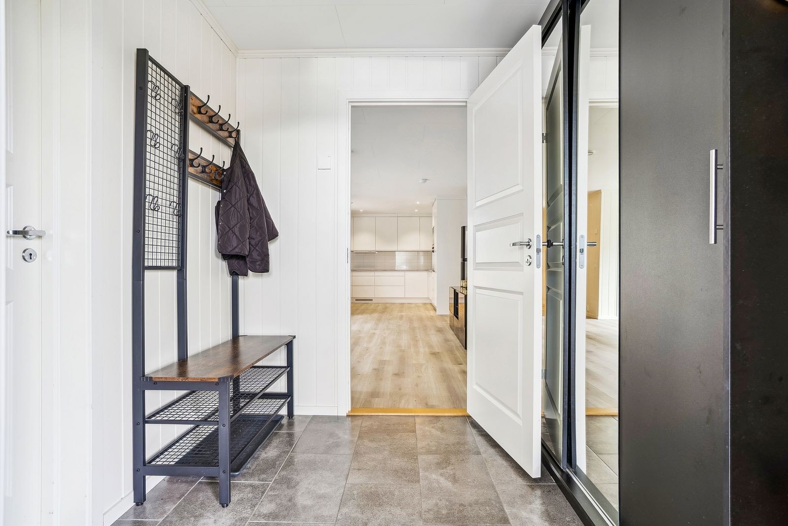 Innbydende entré med flislagt gulv, downlights i himlingen og gulvvarme. Praktisk garderobeskap gir god oppbevaringsplass. Galleribilde