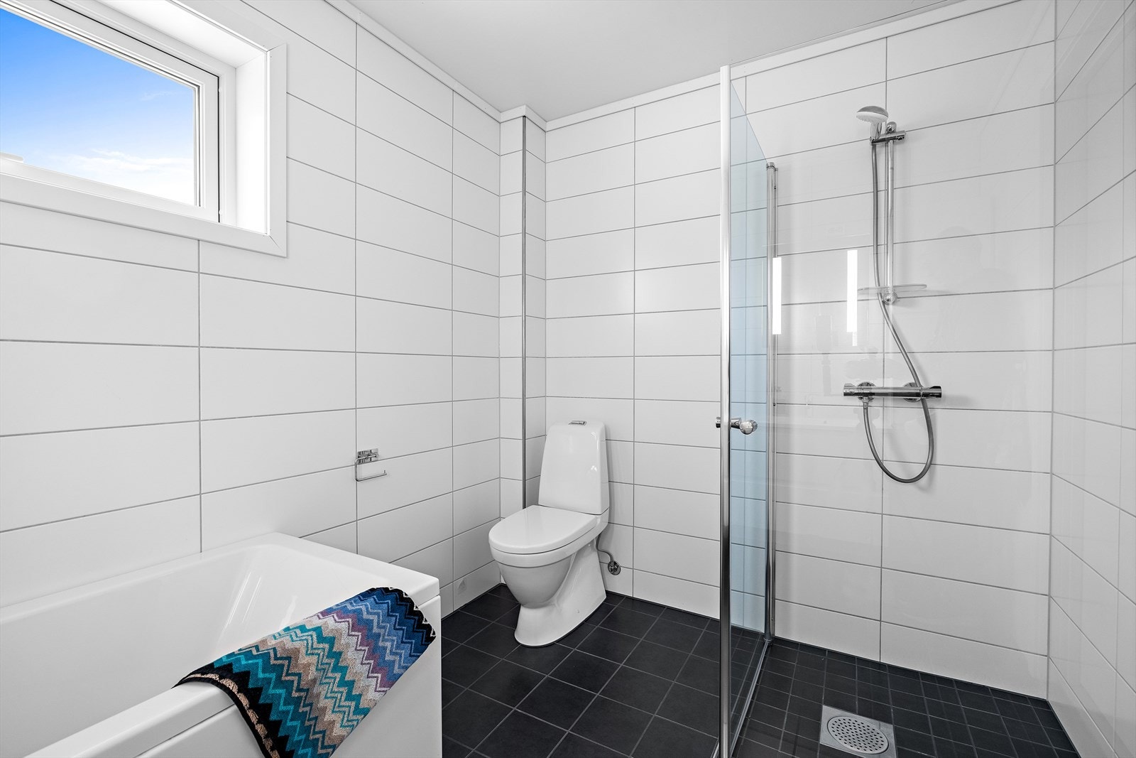 I tillegg til badekar har badet en praktisk dusjnisje med glassdører. Galleribilde