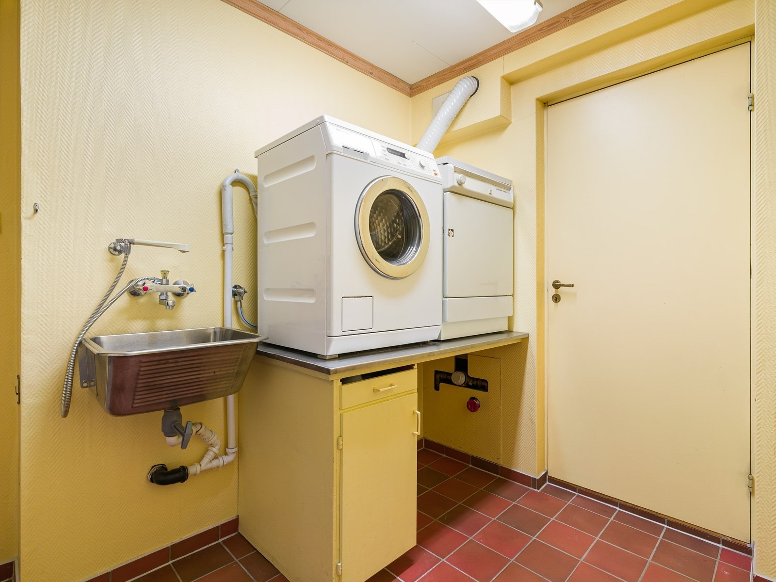 Vaskerom med direkte utgang til garasje. Fliser på gulv lagringsplass og utslagsvask. Galleribilde