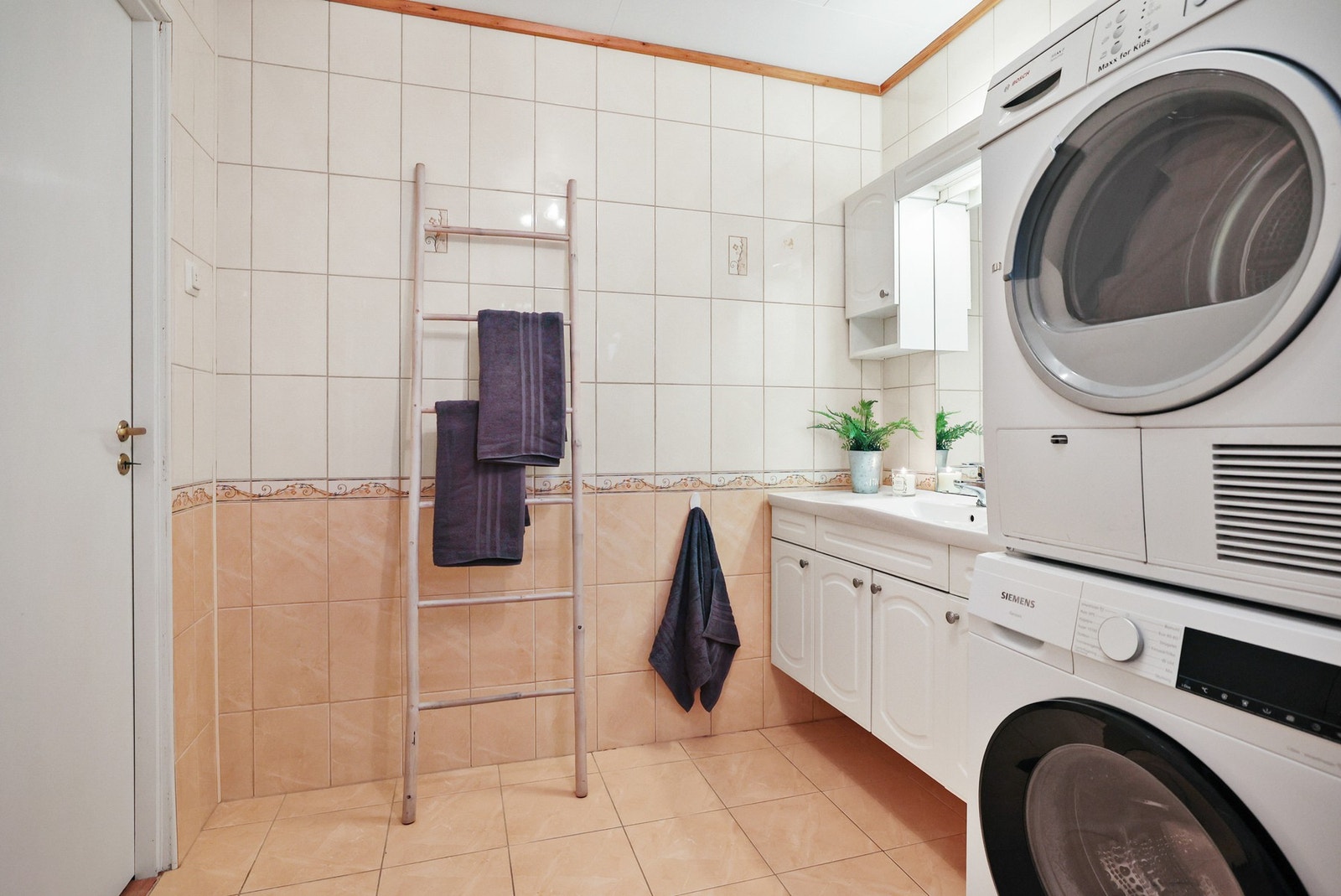 Baderommet inneholder et ekstra vegghengt skap, dusjkabinett, gulvstående toalett og opplegg for vaskemaskin. Galleribilde