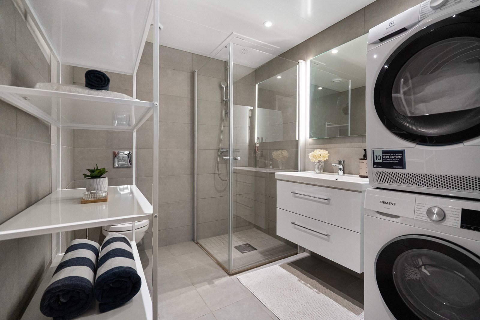 Flislagt baderom med opplegg for vaskemaskin og plass til tørketrommel. Galleribilde