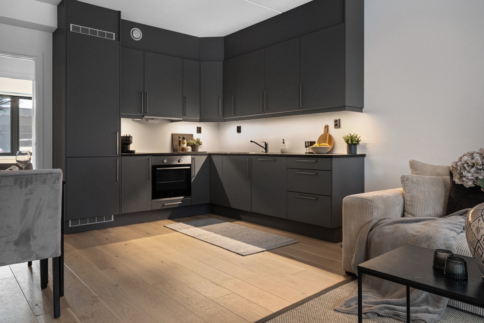 Kjøkkenet fra 2023 har en stilren og moderne innredning med glatte, grå fronter og laminert benkeplate med oppvaskkum og kjøkkenkran. Galleribilde