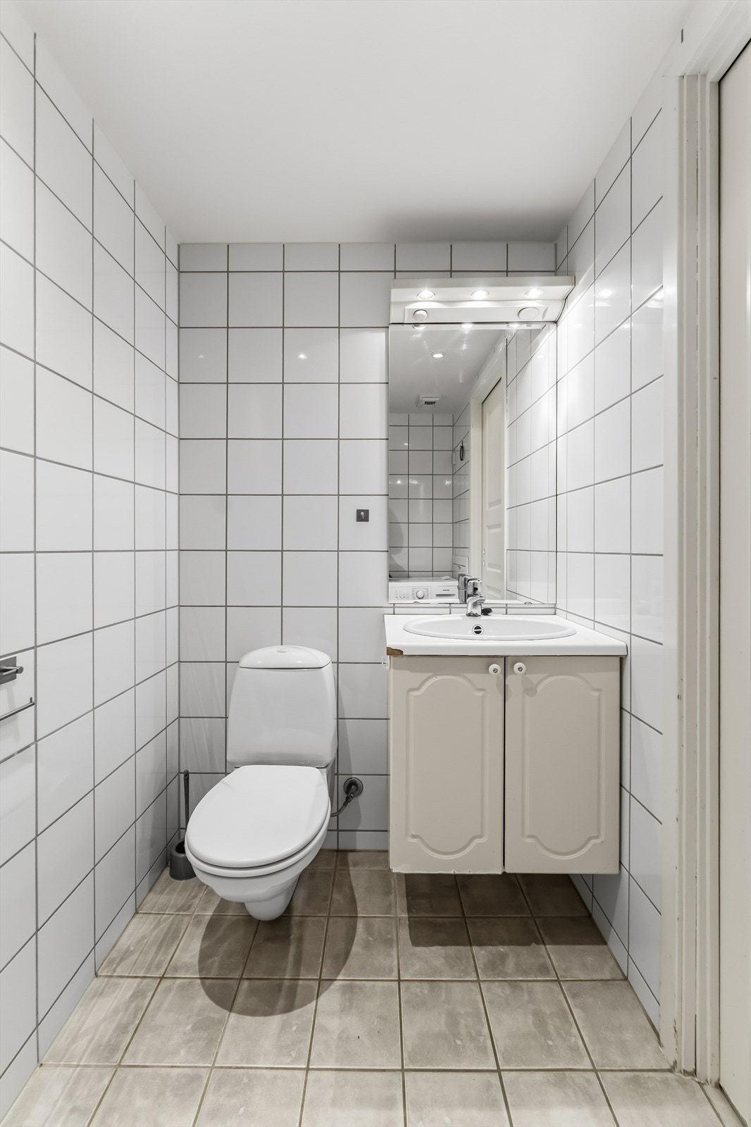 Servant i baderomsinnredning med speil og belysning over. Galleribilde