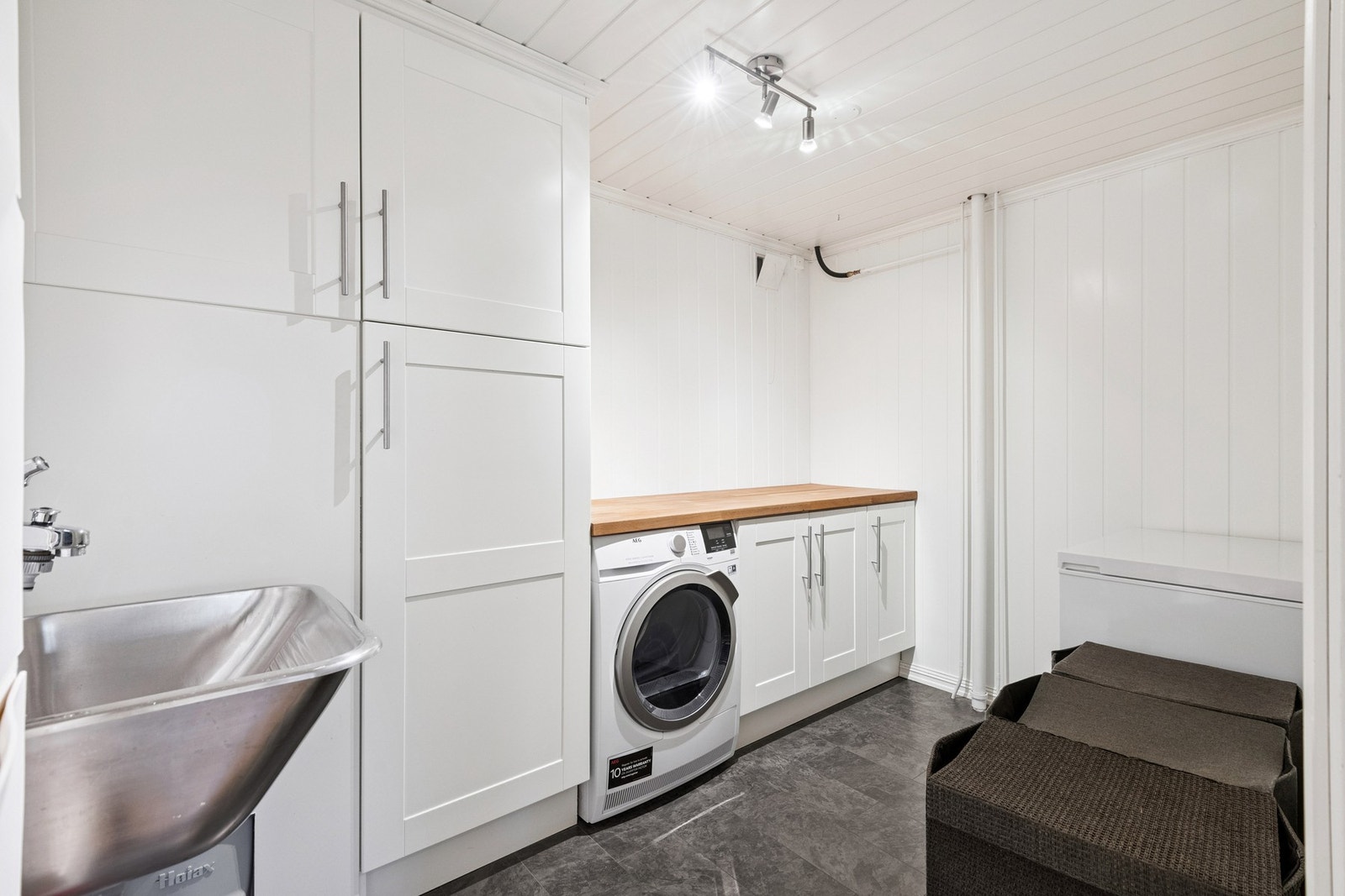 Bod innredet med utslagsvask, skap og opplegg for tørketrommel. Galleribilde