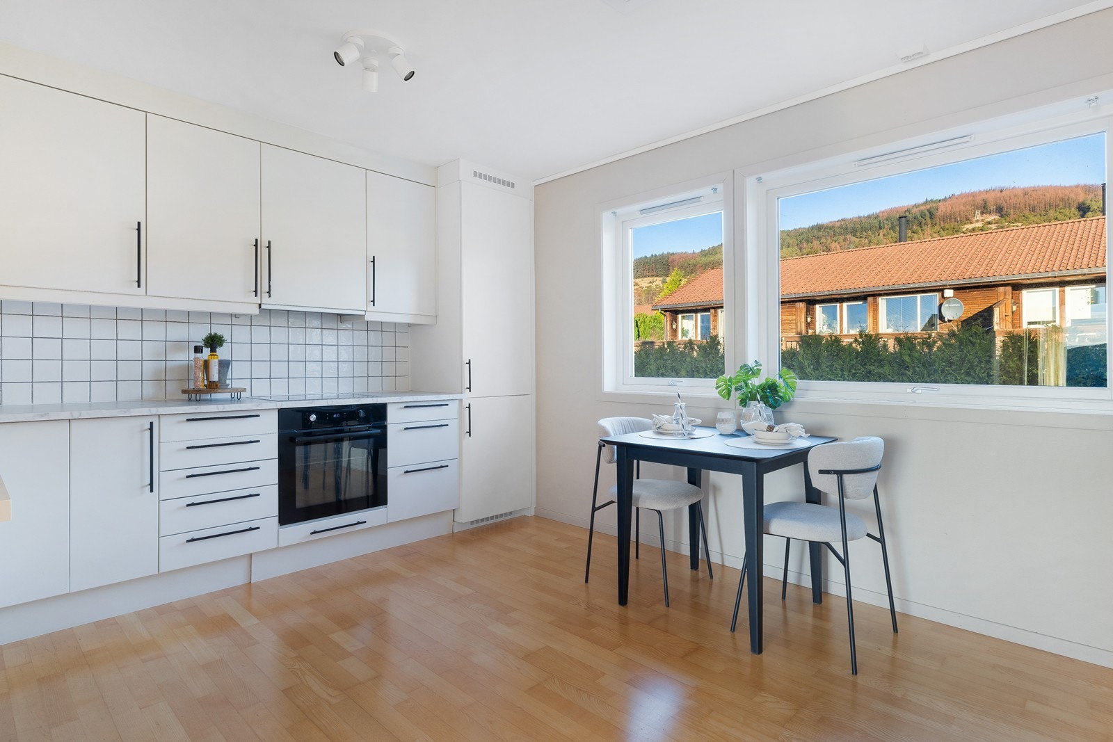 Kjøkkenet har hvite slette fronter og laminat benkeplate, med integrerte hvitevarer for praktisk bruk. Galleribilde