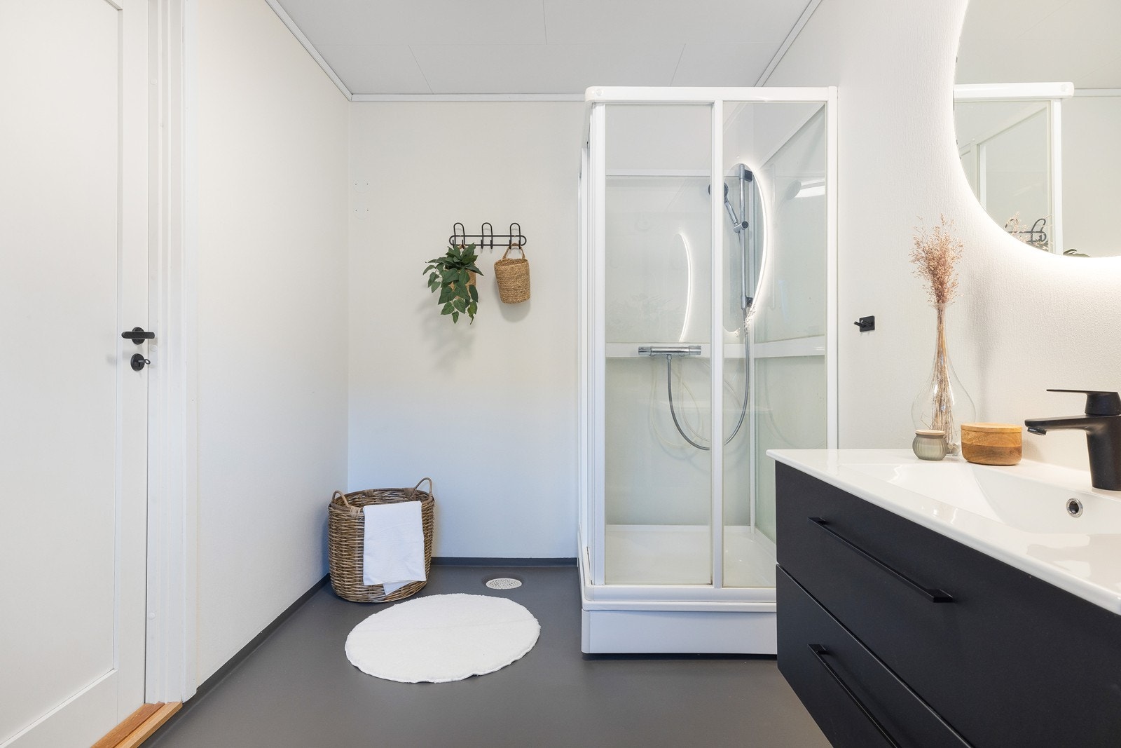 Helstøpt servant med store skuffer under og tilhørende speil. Dusjkabinett i hjørnet. Galleribilde