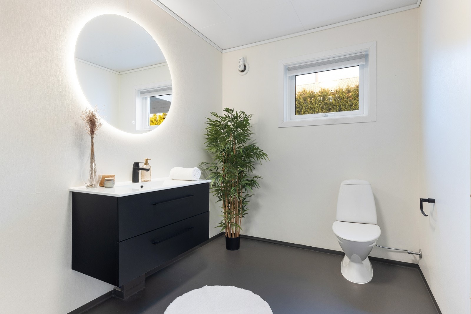 Romslig baderom, med tapet på vegger og belegg på gulv. Nyere servant i møbel og speil på vegg. Galleribilde