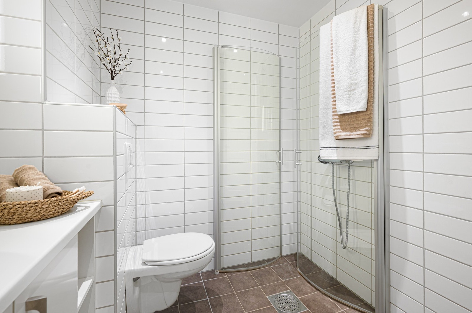 Badet er innredet med åpen dusjløsning med innfellbare dusjdører, vegghengt toalett og opplegg til vaskemaskin. Galleribilde