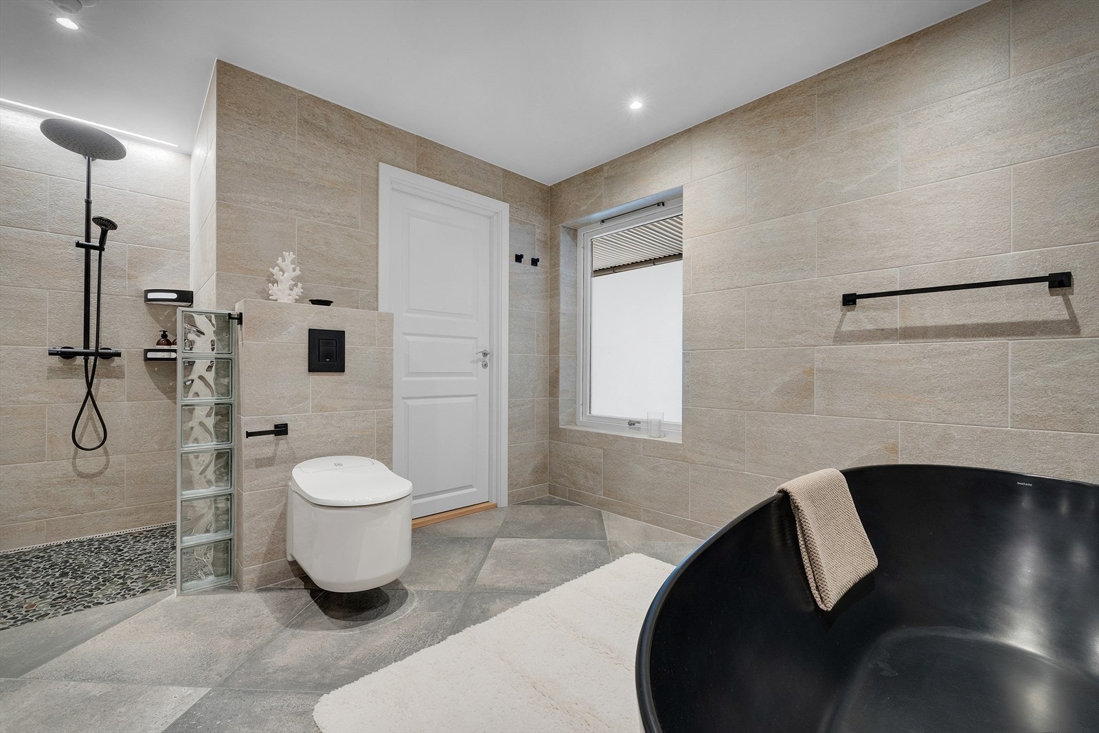 Romslig bad med dusj, badekar og toalett i en helhetlig løsning. Galleribilde