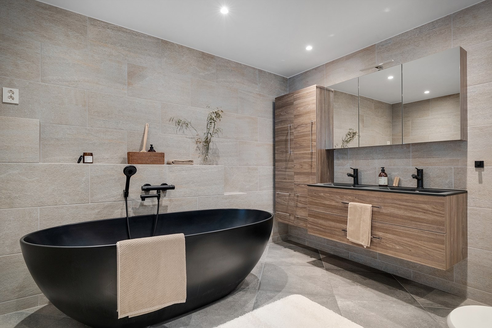BaEksklusivt bad med sort frittstående badekar og moderne innredning. Galleribilde