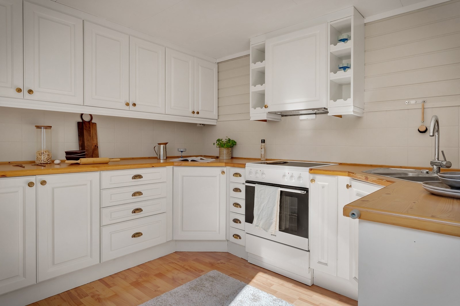 Romslig kjøkken med hvite fronter og heltre benkeplater. Galleribilde